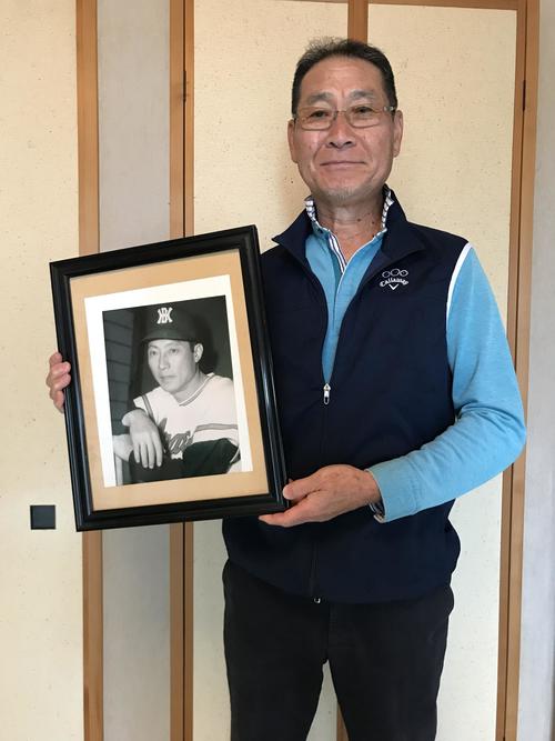 在りし日の戸倉勝城氏の写真を持つ三男の恒城氏