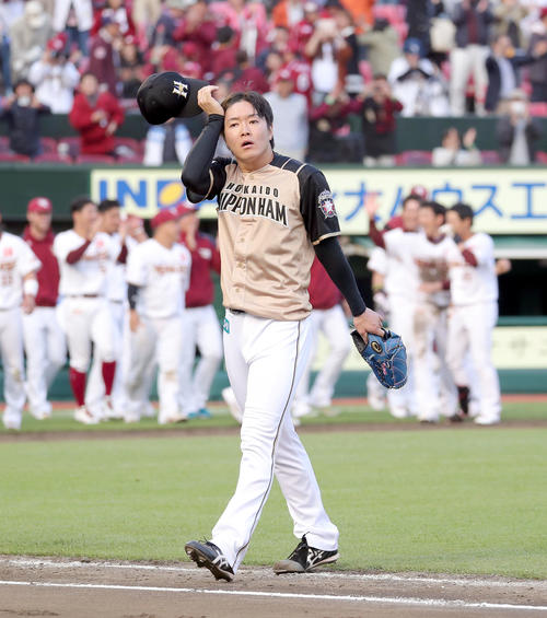 楽天対日本ハム　喜ぶ楽天ナインを背に汗を拭いながら引き揚げる日本ハム玉井（撮影・佐藤翔太）
