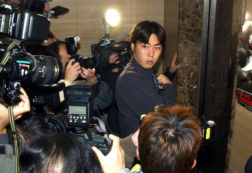 加藤弁護士に遅れて契約更改に向かった上原は、報道陣に囲まれ厳しい表情を見せる（2003年11月27日撮影）