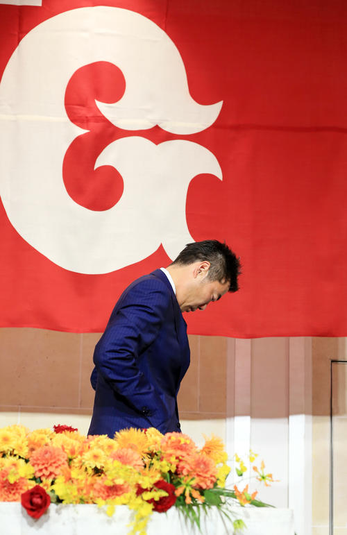 引退会見を終えて、球団旗を背にうつむく巨人上原（撮影・浅見桂子）