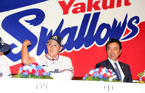ヤクルト新入団発表会で自慢の力こぶを披露するドラフト2位の中山（左）。右は小川監督（2018年12月7日）