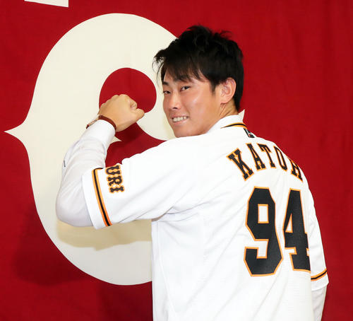 支配下登録会見で、球団旗の前で背番号「94」のユニホームでガッツポーズする加藤（撮影・浅見桂子）