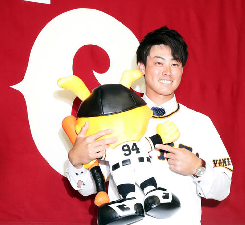 支配下登録会見で、球団旗の前で背番号「94」のマスコット人形を手に笑顔を見せる加藤（撮影・浅見桂子）