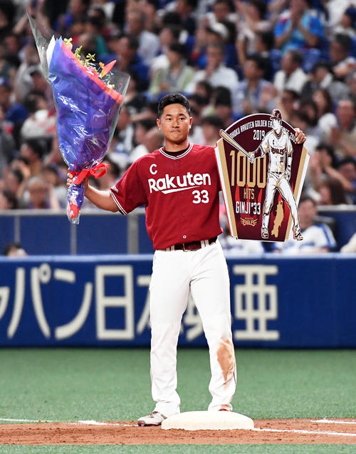5回表楽天1死満塁、右前適時打で1000本安打を達成した銀次は花束とボードを手にファンの声援に応える（撮影・前岡正明）