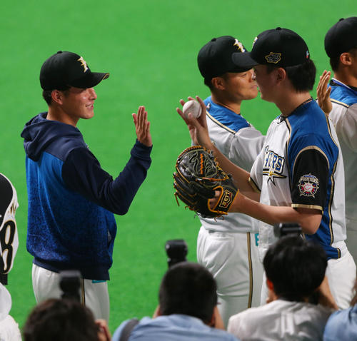 日本ハム対広島　プロ初勝利の日本ハム吉田（左）は石川直から勝利球を手渡され笑顔を見せる（撮影・垰建太）