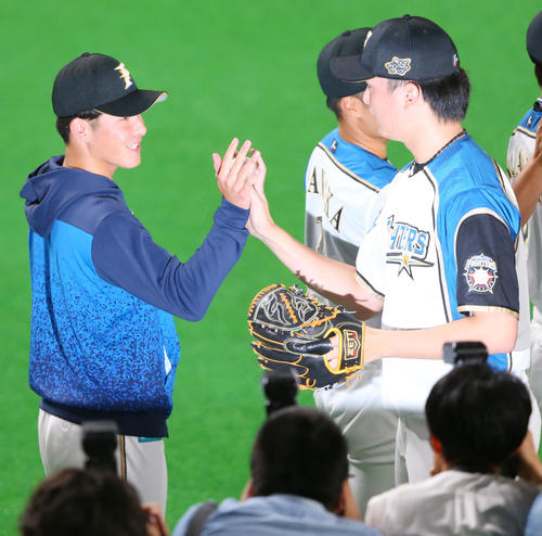 日本ハム対広島　プロ初勝利の日本ハム吉田（左）は石川直から勝利球を手渡され笑顔を見せる（撮影・垰建太）
