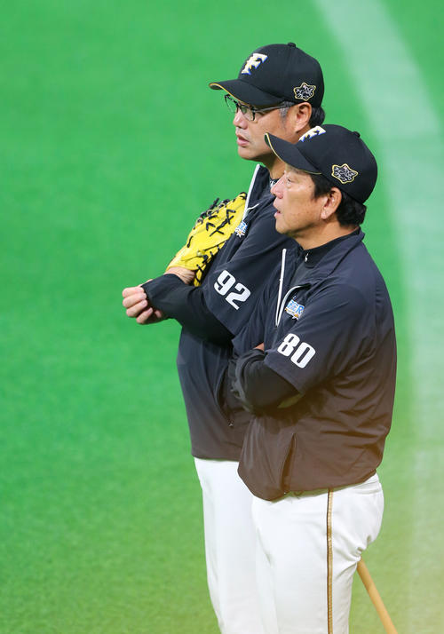 練習中に木田投手チーフコーチ（奥）と話す栗山監督（撮影・垰建太）