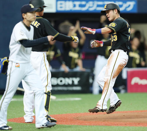 オリックス対阪神　6回表阪神2死二塁、大山の勝ち越し適時打で生還し、福留（左）とタッチを交わす糸原。手前は投手山岡（撮影・前田充）