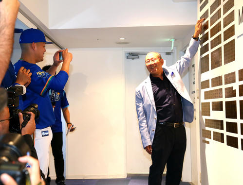 DeNA球団創設70周年を記念したプレートを披露する平松氏（右）をスマートフォンで撮影する筒香（撮影・足立雅史）
