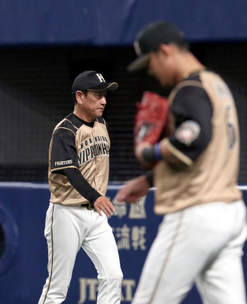 中日対日本ハム　選手交代を告げベンチに戻る日本ハム栗山監督。右手前は中田（撮影・佐藤翔太）