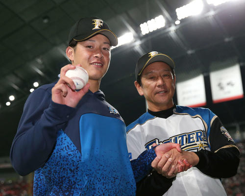 12日、プロ初登板初勝利を挙げウイニングボールを手に笑顔の日本ハム吉田輝（左）。右は栗山監督