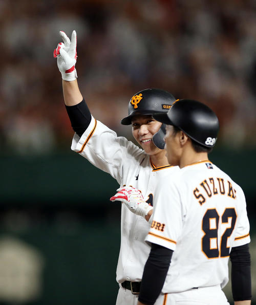 巨人対DeNA　6回裏巨人無死一、三塁、適時打を放ち、ベンチの声援に笑顔で応える坂本勇（左）。右は鈴木コーチ（撮影・狩俣裕三）