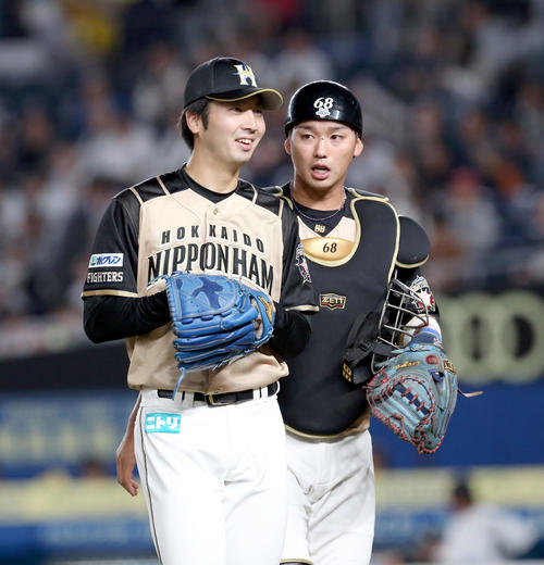 ロッテ対日本ハム　笑顔でベンチに戻る日本ハム鈴木と石川亮（右奥）（撮影・佐藤翔太）