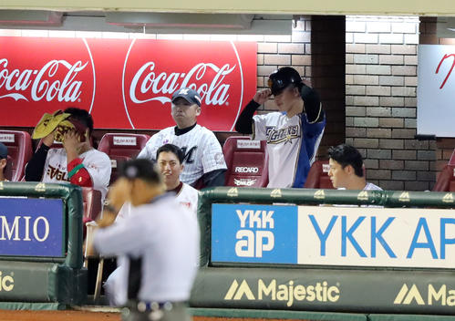全イ対全ウ　6回表全イ、一塁コーチを務める日本ハム吉田輝（後方）はベンチで巨人のヘルメットをかぶる（撮影・垰建太）