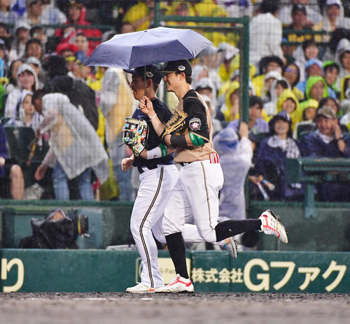 プロ野球オールスター第2戦　全セ対全パ　5回の守備を終えかさを差しながらベンチに戻る日本ハム西川遥輝、左はオリックス吉田正尚（撮影・清水貴仁）