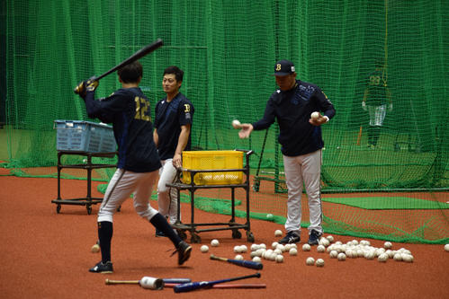 打撃練習を行う佐野にボールをトスする西村監督