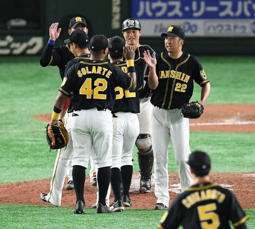 巨人対阪神　今季初セーブの藤川（右）はチームメートとタッチをかわす（撮影・山崎安昭）