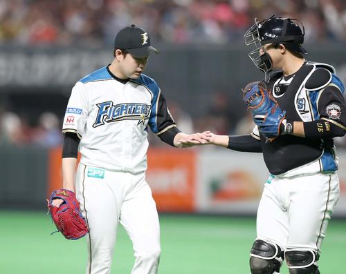 日本ハム対ソフトバンク　1回を投げ終えベンチに戻る堀（左）は宇佐見とタッチする（撮影・黒川智章）
