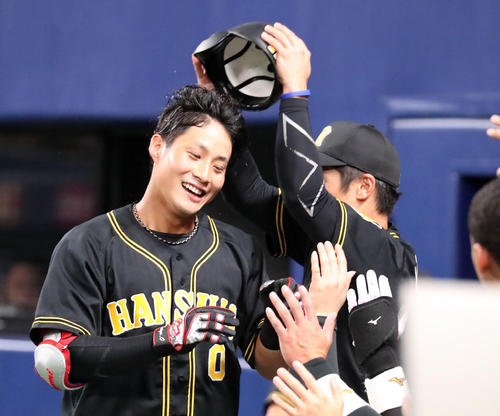 中日対阪神　6回表阪神2死、木浪は右越え本塁打を放ちベンチの坂本（右）からヘルメットを取られ笑顔でタッチ（撮影・加藤哉）