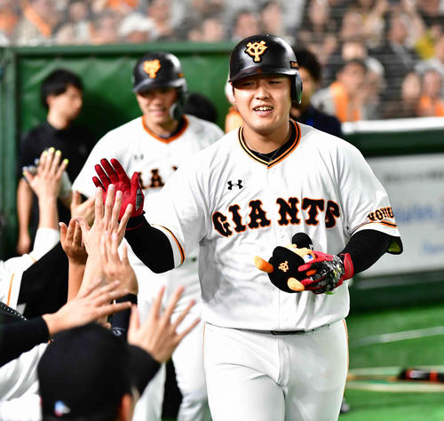 巨人対阪神　4回裏巨人1死一塁、岡本は右越えに逆転2点本塁打を放ちベンチのナインの祝福を受ける。後方左は坂本勇（撮影・小沢裕）