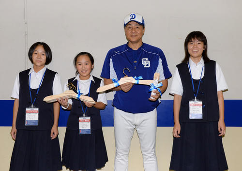 中日対DeNA　試合前、手作りハンガープロジェクトを行っている長野県天龍村の天竜中学校生徒からヒノキを材料に作られたハンガーを受け取り記念撮影に応じる与田剛監督（撮影・森本幸一）