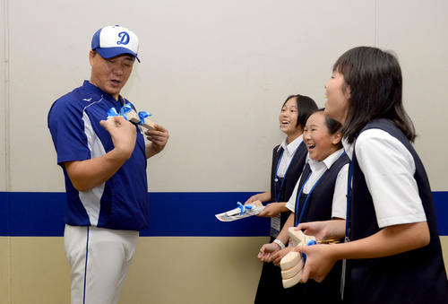 中日対DeNA　試合前、手作りハンガープロジェクトを行っている長野県天龍村の天竜中学校生徒からヒノキを材料に作られた監督用に大きく作られたハンガーを笑顔で受け取り体にあわせる与田剛監督（撮影・森本幸一）