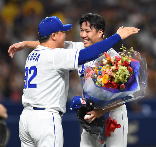 中日対阪神　ノーヒットノーランを達成し、花束を手に与田監督（左）と抱き合う大野雄（撮影・森本幸一）
