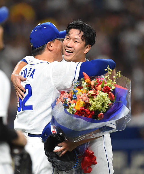 中日対阪神　ノーヒットノーランを達成し、花束を手に与田監督（左）と抱き合う大野雄（撮影・森本幸一）