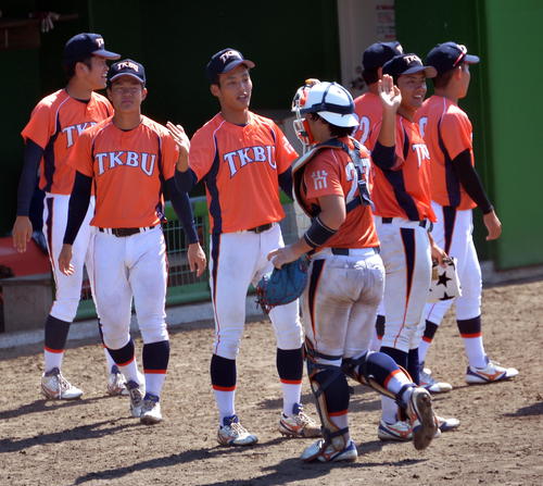 東北公益文科大対山形大　イニングの合間にベンチから仲間を出迎える東北公益文科大・石森主将（中央）