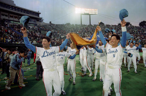 90年10月、日本シリーズ第4戦で巨人を下して優勝し、ペナントを掲げて球場内を回る西武辻（右手前）。左手前は石毛