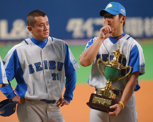 松坂大輔は優勝セレモニー中にトロフィーを手に「シー」と指を立てる。左はシリーズMVP石井貴（2004年10月25日）