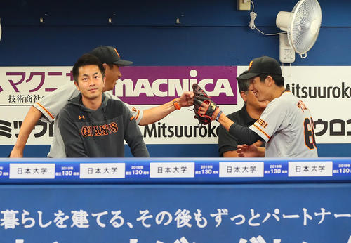 DeNA対巨人　初回を無失点に抑えた巨人戸郷（右）は宮本コーチ（後方左）の出迎えにタッチと笑顔で応える（撮影・足立雅史）