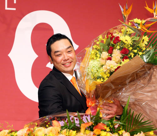 引退会見でサプライズ登場したチームメートから贈られた花束を両手に抱え笑みを浮かべる巨人阿部（撮影・垰建太）