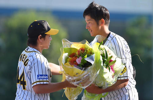 引退セレモニーで同期入団の梅野隆太郎（左）から花束を受け取る横田慎太郎（撮影・上田博志）