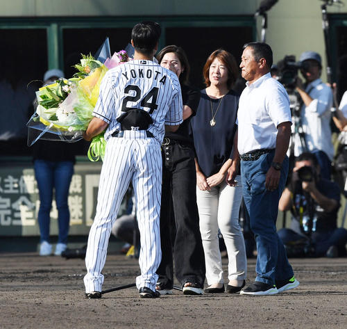 横田慎太郎（左）は家族から花束を受け取る、1人おいて左から、姉の真子さん、母・まなみさん、父・真之さん（撮影・奥田泰也）