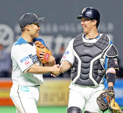 握手を交わしながらベンチに戻る日本ハム田中賢と鶴岡（右）（撮影・佐藤翔太）