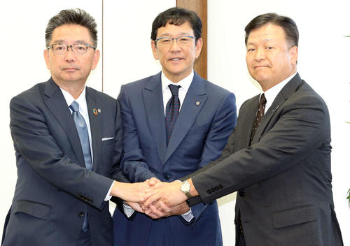 続投が決まった日本ハムの栗山監督（中央）は、畑オーナー（右）と川村球団社長（左）と笑顔で握手する（撮影・浅見桂子）