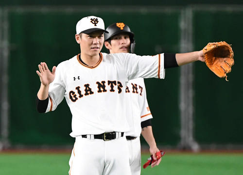 けん制球の練習で投手に合図を送る巨人坂本勇。後方は陽（撮影・山崎安昭）