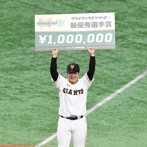 SファイナルステージでMVPの巨人岡本はボードを掲げて笑顔を見せる（撮影・奥田泰也）