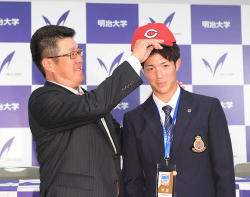 1位指名した明大・森下（右）に帽子をかぶせる広島佐々岡監督（撮影・加藤諒）