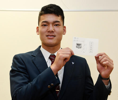 与田監督のメッセージが書かれた交渉権確定の当たりくじを手に笑顔を見せる石川（撮影・前岡正明）