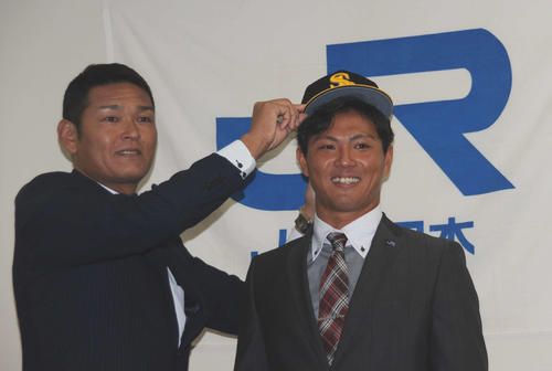 ソフトバンクのドラフト1位、JR西日本の佐藤（右）は、永井編成育成本部長兼スカウト育成部長に帽子をかぶせられて笑顔を見せる（撮影・浦田由紀夫）
