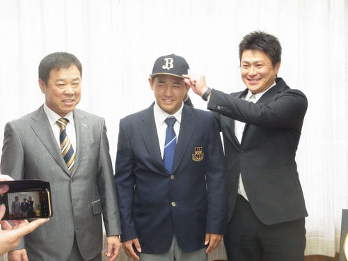 オリックスの1位指名を受け、担当の縞田スカウト（右）から帽子をかぶせてもらう興南・宮城（中央、左は福良GM）（撮影・堀まどか）