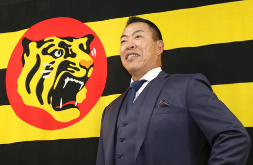 球団旗をバックにポーズを取る井上一樹新コーチ（撮影・白石智彦）