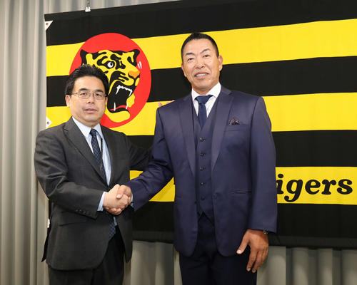 就任会見を終え、阪神谷本球団副社長（左）とがっちり握手する井上新コーチ（撮影・白石智彦）