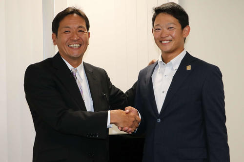 日本ハムからドラフト4位指名を受け、坂本スカウト（左）と握手を交わして笑顔を見せるJX－ENEOS・鈴木（撮影・山崎純一）
