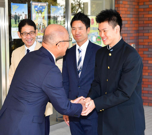 阪神の畑山俊二統括スカウト（手前）から指名あいさつを受け笑顔で握手を交わすドラフト3位の横浜・及川雅貴（右）、左から横浜・葛蔵造校長、高山大輝監督代行（撮影・清水貴仁）