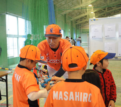 チビッコファンにお菓子をプレゼントする加藤球団社長補佐（正面）
