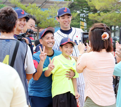 那覇市内の小学校を訪問し、児童と記念撮影する秋山（右）と山崎（撮影・浅見桂子）