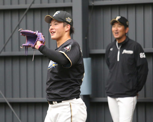 サンマリン宮崎のブルペンで投球練習を終えて笑顔の日本ハム吉田輝。右は加藤2軍投手コーチ（撮影・木下大輔）